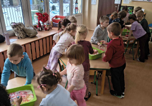 Dzieci barwią śnieg pipetami z farbą.