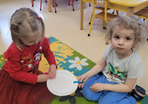 Chłopiec z dziewczynką wykonują ćwiczenie ze spinaczami.