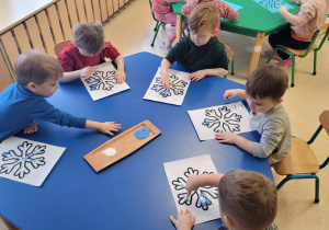 Dzieci wypełniają kontur śnieżynki farbą.