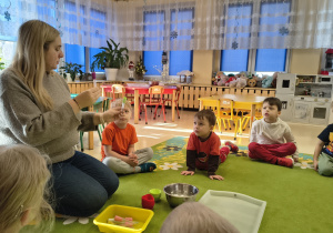 Nauczycielka pokazuje dzieciom jak wygląda pipetka.