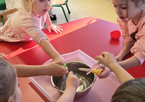 Dzieci napełniają wodą foremki za pomocą pipetki.