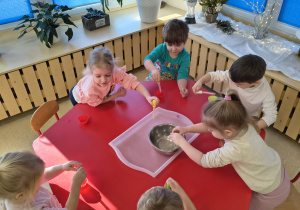 Dzieci napełniają wodą foremki.