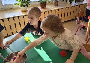 Dzieci napełniają wodę do pipetek z miski.