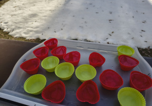 Prezentacja napełnionych foremek wystawionych za okno.