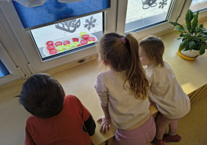 Dzieci obserwują foremki wypełnione wodą.