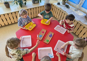 Dzieci malują farbami lodowe babeczki.