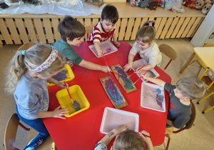 Dzieci mieszają kolory podczas zabarwiania lodowych babeczek.