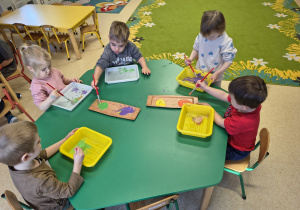 Dzieci eksperymentują z lodem i farbą.