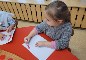 Dziewczynka tworzy kształt serca techniką stemplowania.