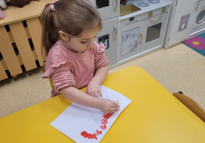 Dziewczynka wykonuje proponowaną pracę plastyczną.