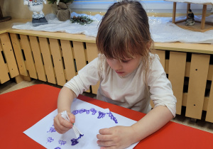 Dziewczynka wykonuje pracę plastyczną.