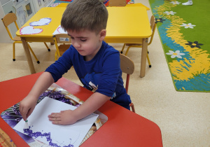 Chlopiec uczestniczy w zabawach plastycznych z farbą.