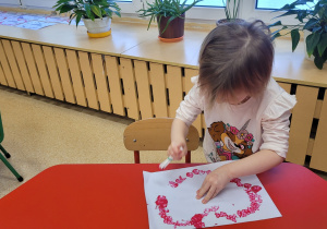 Dziewczynka wykonuje serduszko dla Babci i Dziadka.