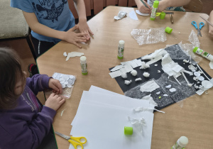 Dzieci układają z kółek origami elementy pracy.