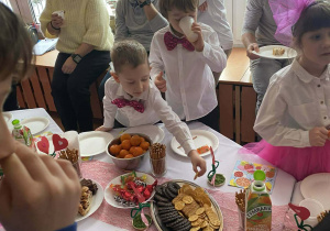 Zaproszeni goście wraz z dziećmi podczas poczęstunku.