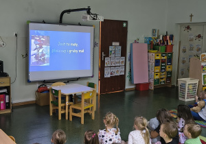 Dzieci oglądają bajkę edukacyjną o misiu.