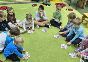 Dzieci siedzą w kole z kartą pracy.