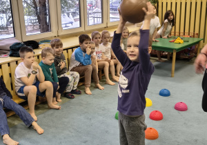 Chłopiec podnosi do góry piłkę lekarską.