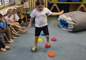 Dziewczynka idzie po kolczastych jeżykach.