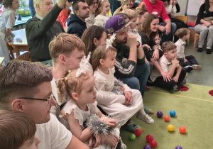 Dzieci wraz z rodzicami obserwują zabawę ruchową.