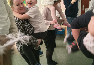 Dzieci z grupy Biedronek tańczą z rodzicami na gazecie.