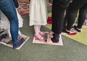 Dzieci z grupy Biedronek tańczą z rodzicami na gazecie.