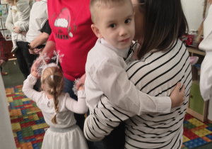 Mama trzyma chłopca na rękach podczas zabawy muzycznej.