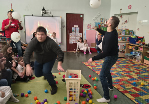 Tatusiowie uczestniczą w zabawie ruchowej z balonem.