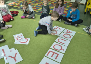 Chłopiec układa takie same samogłoski.