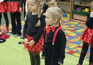 Dziewczynka i chłopczyk stoją na środku i recytują wiersz.