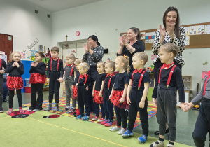 Mali artyści stoją przed publcznością i dziekują za oklaski.