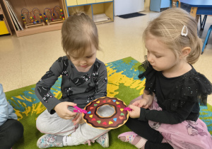 Dzieci podają sobie papierowego pączka za pomocą klamerek.