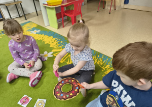 Chłopiec podaje papierowego pączka dziewczynce za pomocą klamerki.