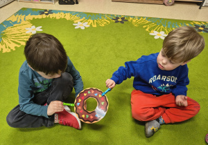 Chłopcy podają sobie papierowego pączka za pomocą klamerek.