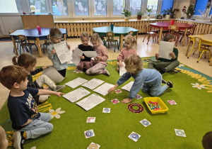 Dzieci oglądają kolorowanki z pączkami.