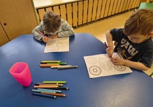 Dzieci kolorują kredkami pączki.