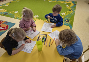 Dzieci kolorują kredkami pączki.