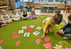 Chłopiec łączy dwie połówki papierowego serca.