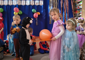 Dzieci przenoszą balon na chuście.