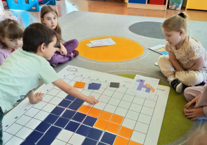 Kodowanie -dzieci zakrywają pola na macie do kodowania zgodnie z instrukcją.