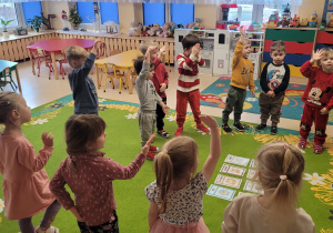 Dzieci śpiewają piosenkę w języku angielskim i naśladują gesty za nauczycielem.