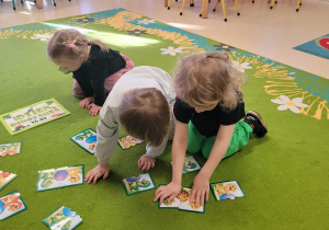 Dzieci układają puzzle z dinozaurami.