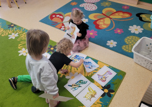 Dzieci wybierają kartę pracy z dinozaurami.