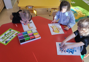 Dzieci wypełniają białe kółeczka odpowiednim kolorem plasteliny.