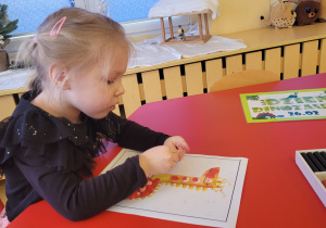 Dziewczynka zgniata w rączkach plastelinę.