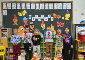 Dzieci z grupy Biedronek prezentują papierowe serduszka walentynkowe.