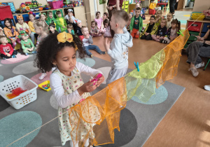 Dziewczynka wiesza chusteczkę i przypina klamerkę.