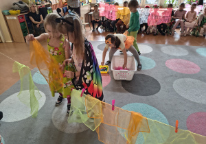 Dziewczynki wspólnie wieszają chustki na sznurku.