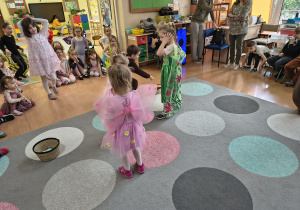 Dzieci sprawdzają czy wszystkie kwiatki zostały zebrane z dywanu.