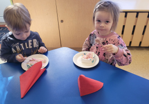 Dzieci jedzą tort urodzinowy.